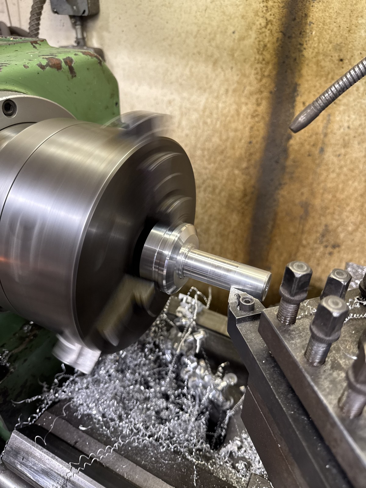 Manual lathe in operation, turning aluminum spindle stock with chips flying